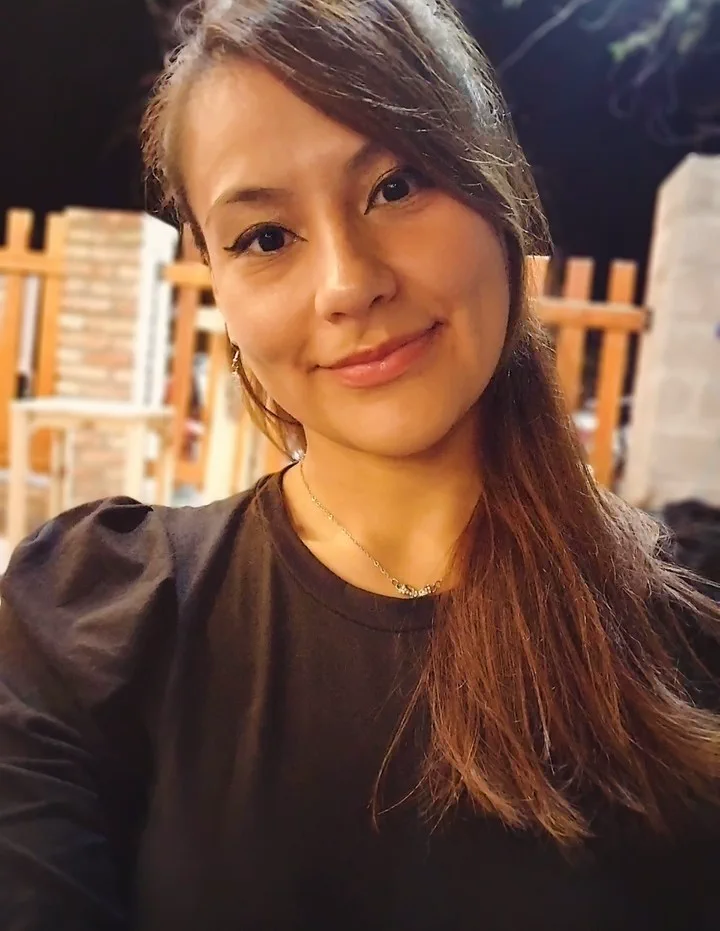 Shadya Altamirano sonríe mirando a la cámara en un plano cercano al aire libre de noche.