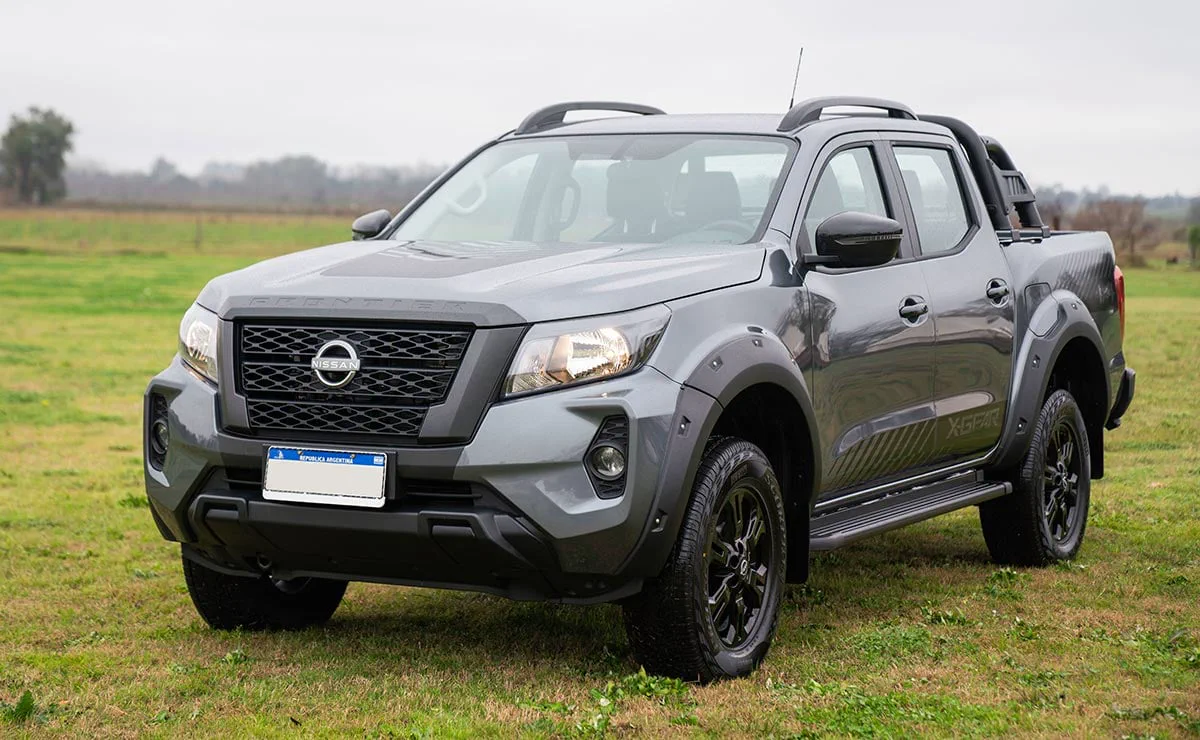 Una camioneta gris oscura de doble cabina se encuentra estacionada sobre el pasto en un descampado.