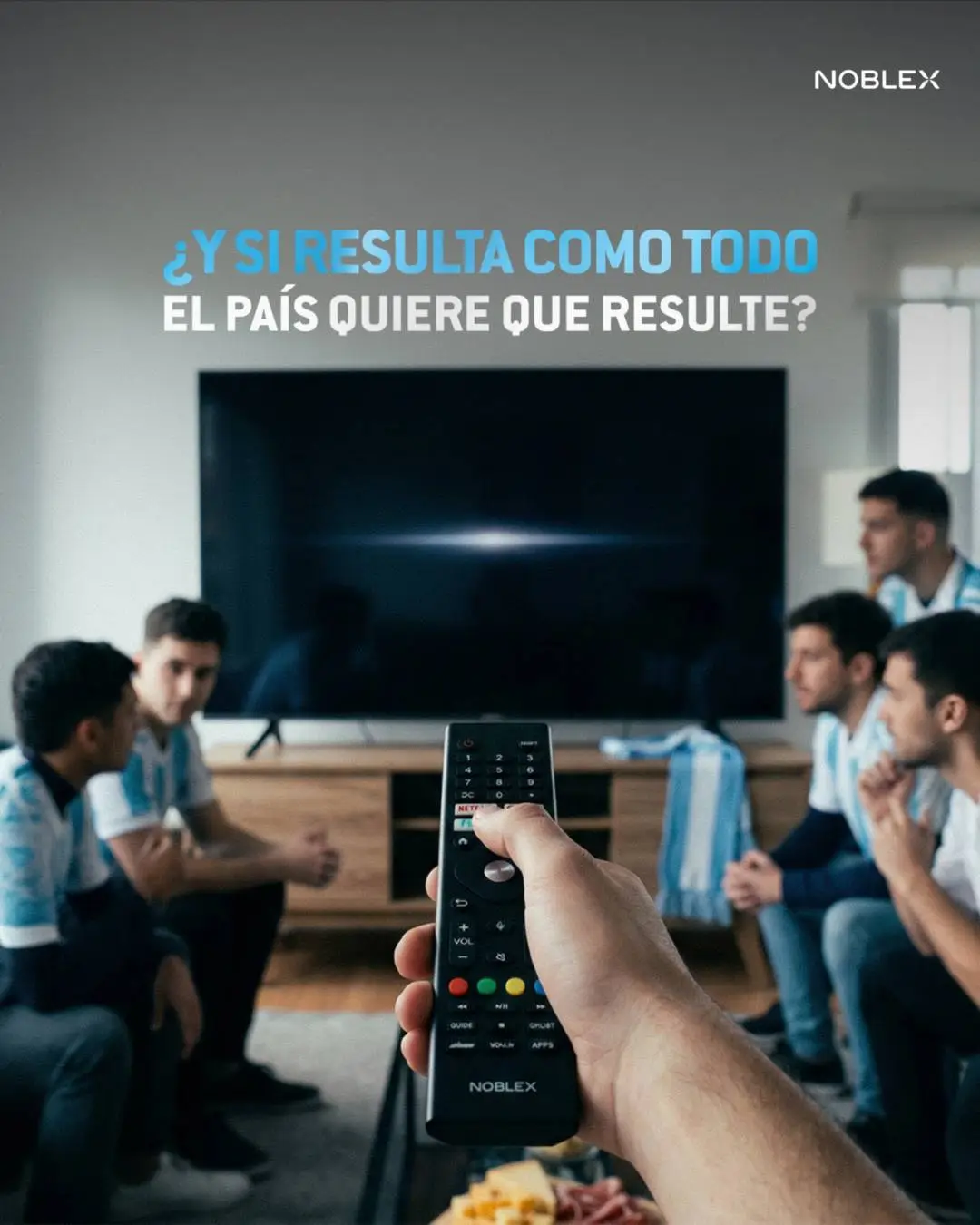 Una persona sostiene un control remoto frente a un televisor apagado rodeada de hinchas argentinos.