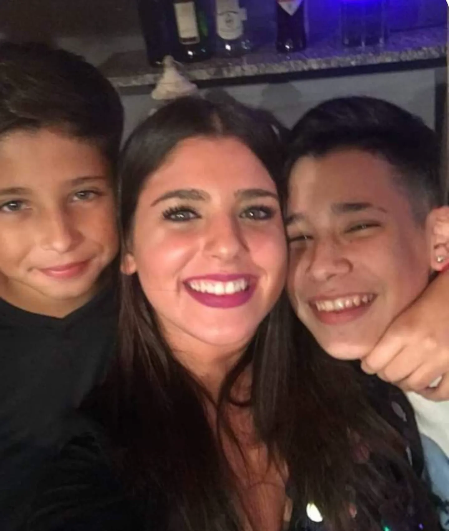 Una chica sonriente saca una selfie junto a dos chicos que sonríen a su lado.