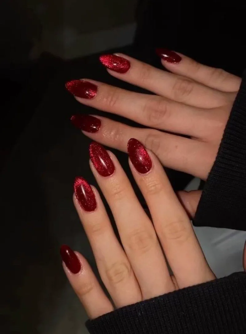 Unas manos lucen unas unas largas y almendradas esmaltadas de rojo brillante.