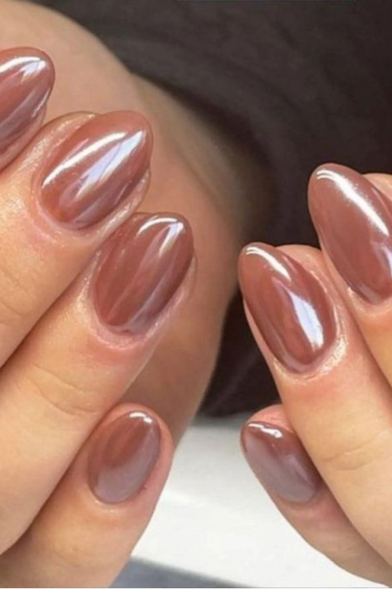 Las uñas de ambas manos están pintadas con esmalte marrón metalizado brillante.