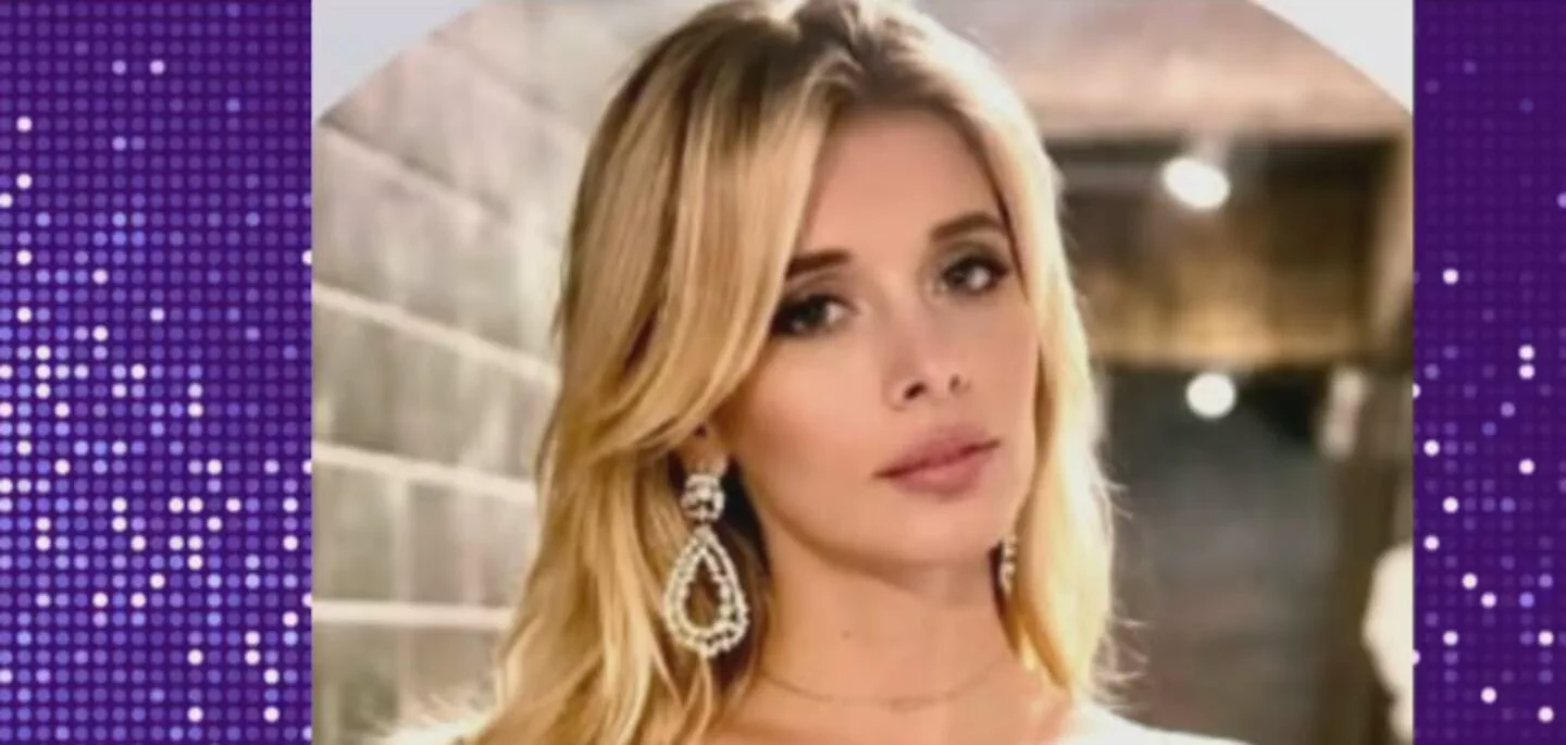 Primer plano de una mujer rubia con aros colgantes brillantes y fondo desenfocado.
