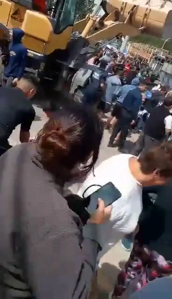 Un grupo de personas y una máquina excavadora amarilla en una calle al aire libre.
