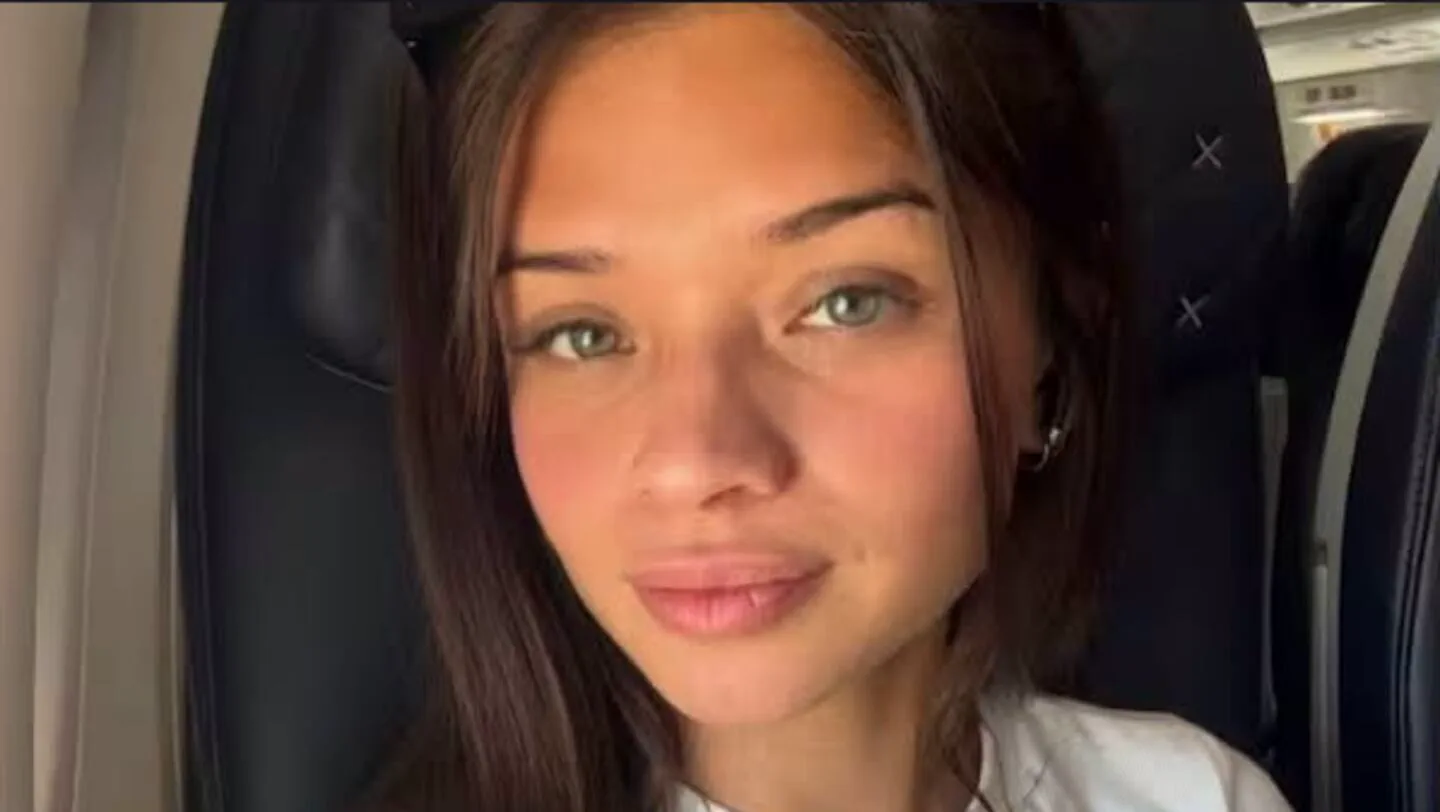 Primer plano de una joven de cabello castaño y ojos claros sentada en el asiento de un avión.