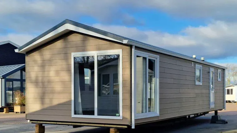 Una casa rodante prefabricada revestida de madera clara se encuentra emplazada al aire libre.